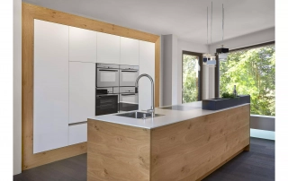 Weiße Küche mit Echtholzfronten, weißer Arbeitsplatte und hochwertigen Elektrogeräten