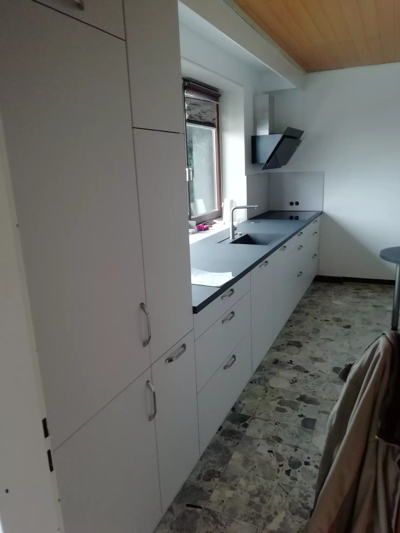 Moderne, weiße Küche mit schwarzer Arbeitsplatte, Seitenansicht