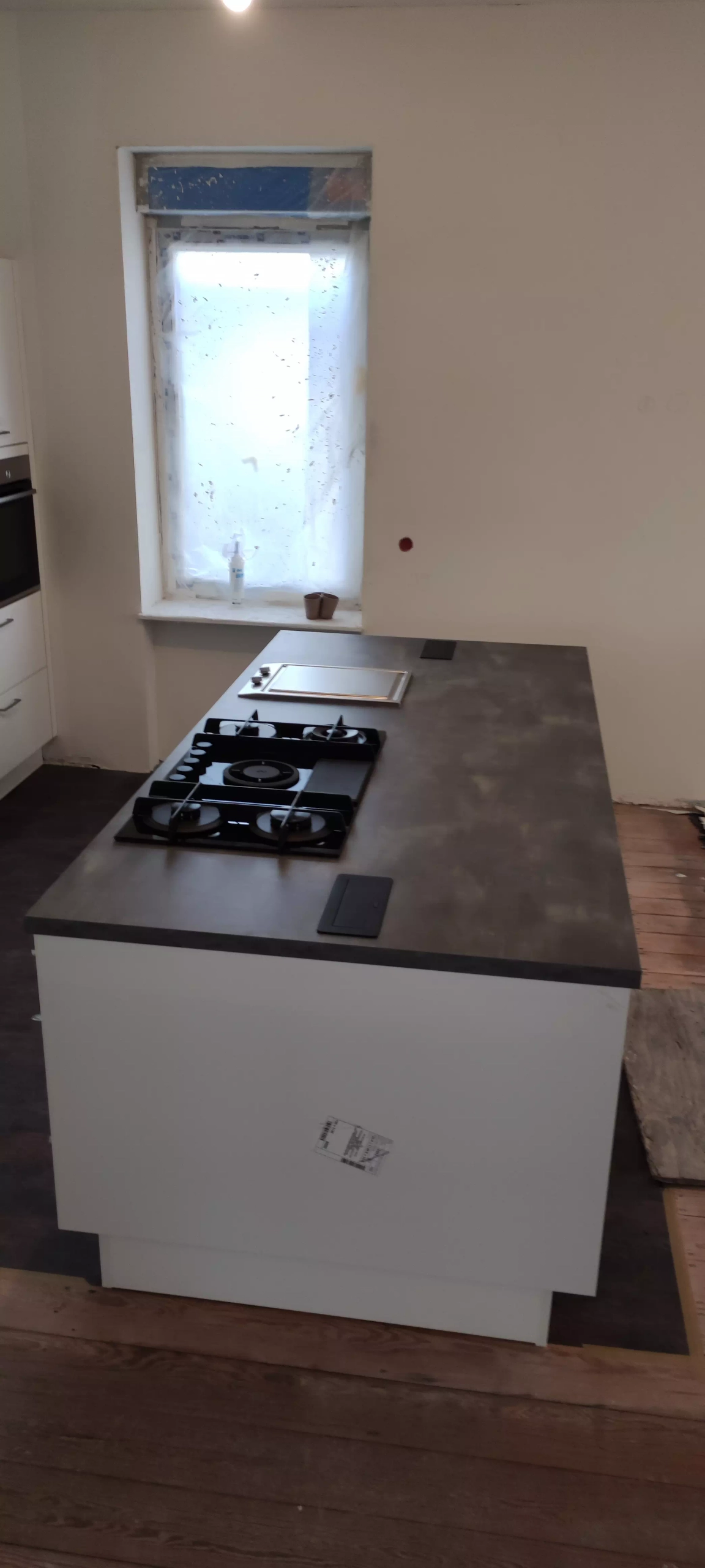 Moderne, weiße Kücheninsel mit schwarzer Arbeitsplatte und Gaskochfeld, von der Seite